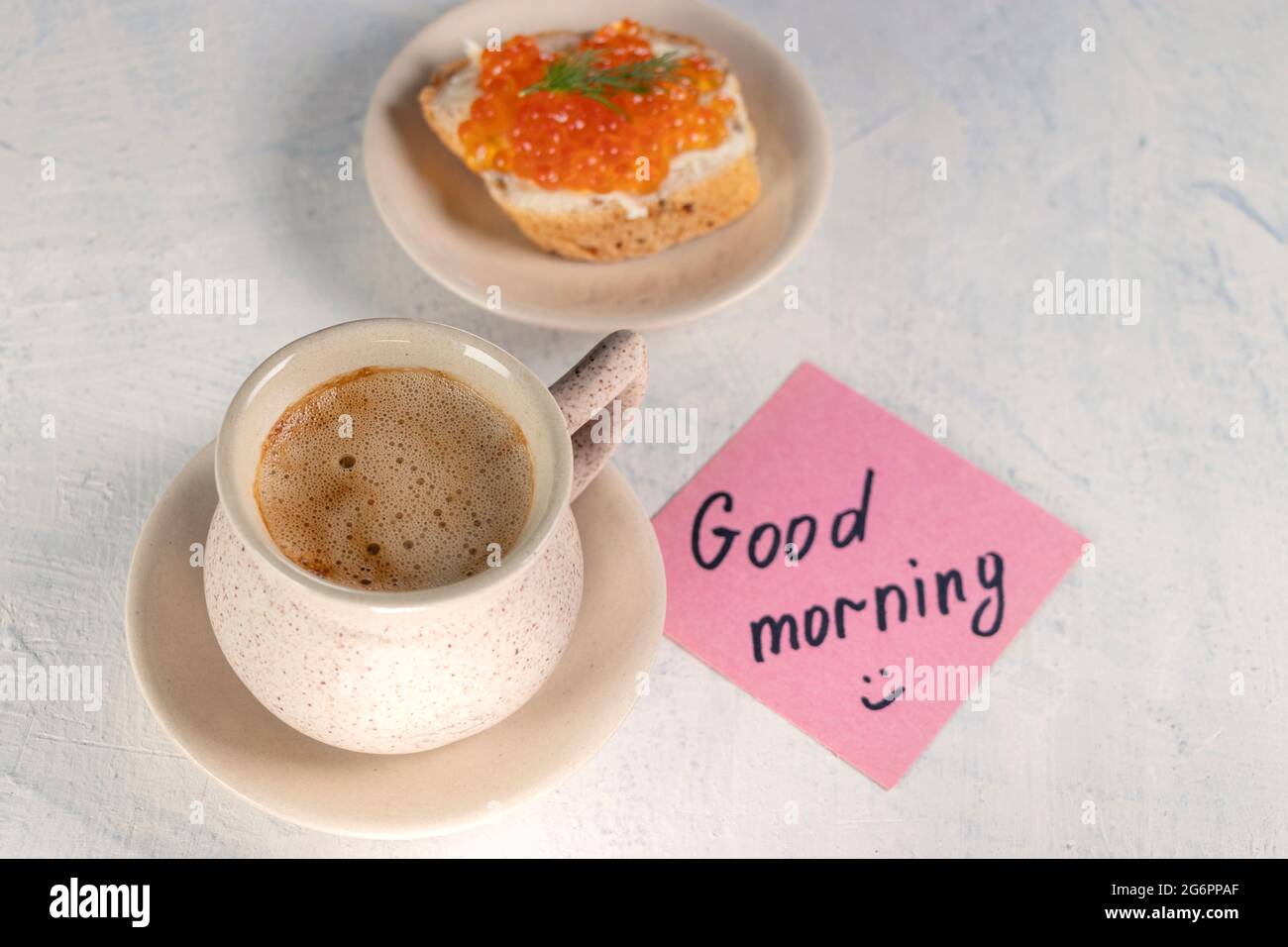 una tazza di caffè con un panino con caviale rosso e accanto a una nota con la scritta buongiorno. vista dall'alto. messa a fuoco morbida Foto Stock