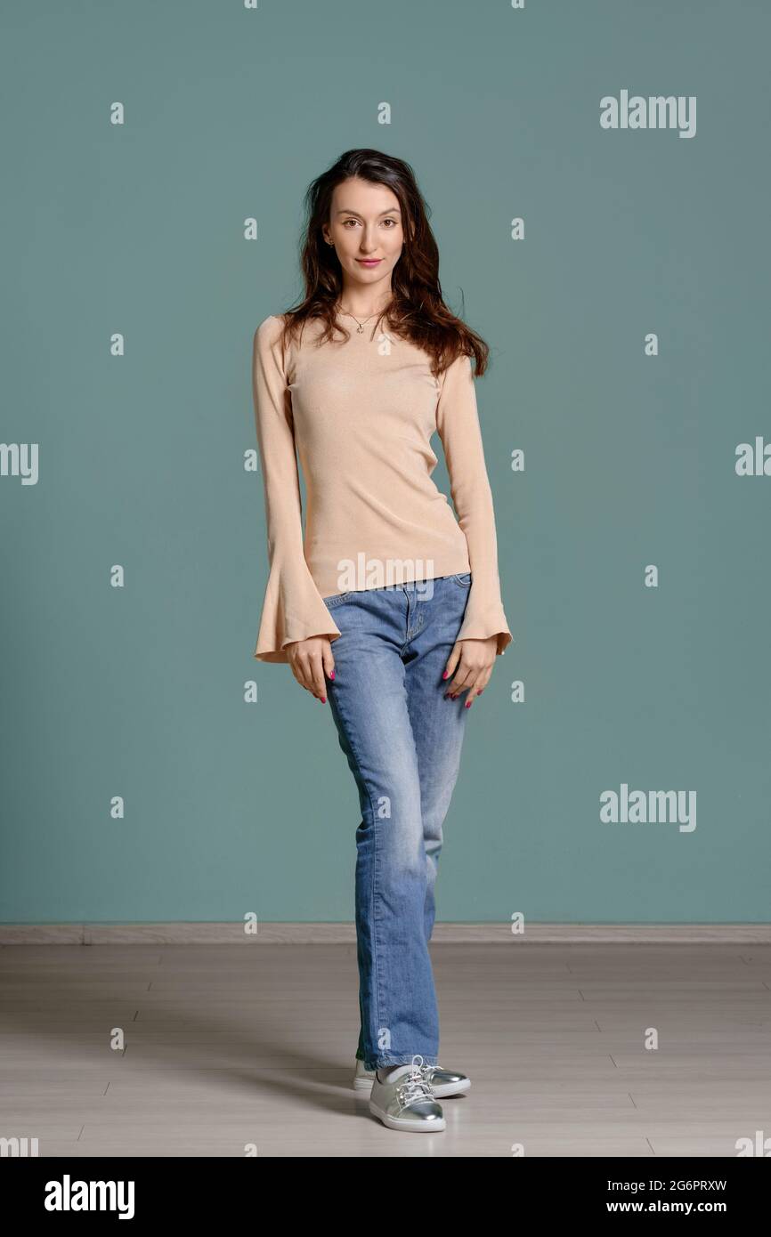 Ritratto a lunghezza intera di giovane donna alla moda in Jersey beige jeans  a manica lunga e blu diritto Foto stock - Alamy