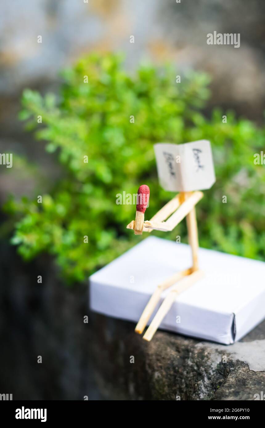 Concetto e idee di matchstick. Concetto e idee di lettura del libro. Matchstick lettura di un libro con sfondo verde. Foto Stock