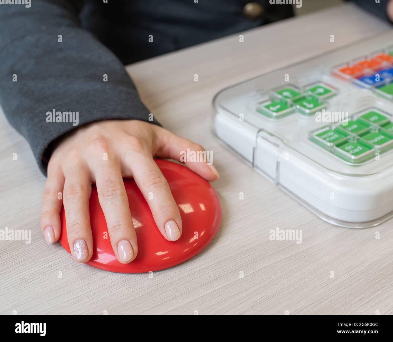 Donna con paralisi cerebrale che lavora su un mouse per computer wireless specializzato. Foto Stock