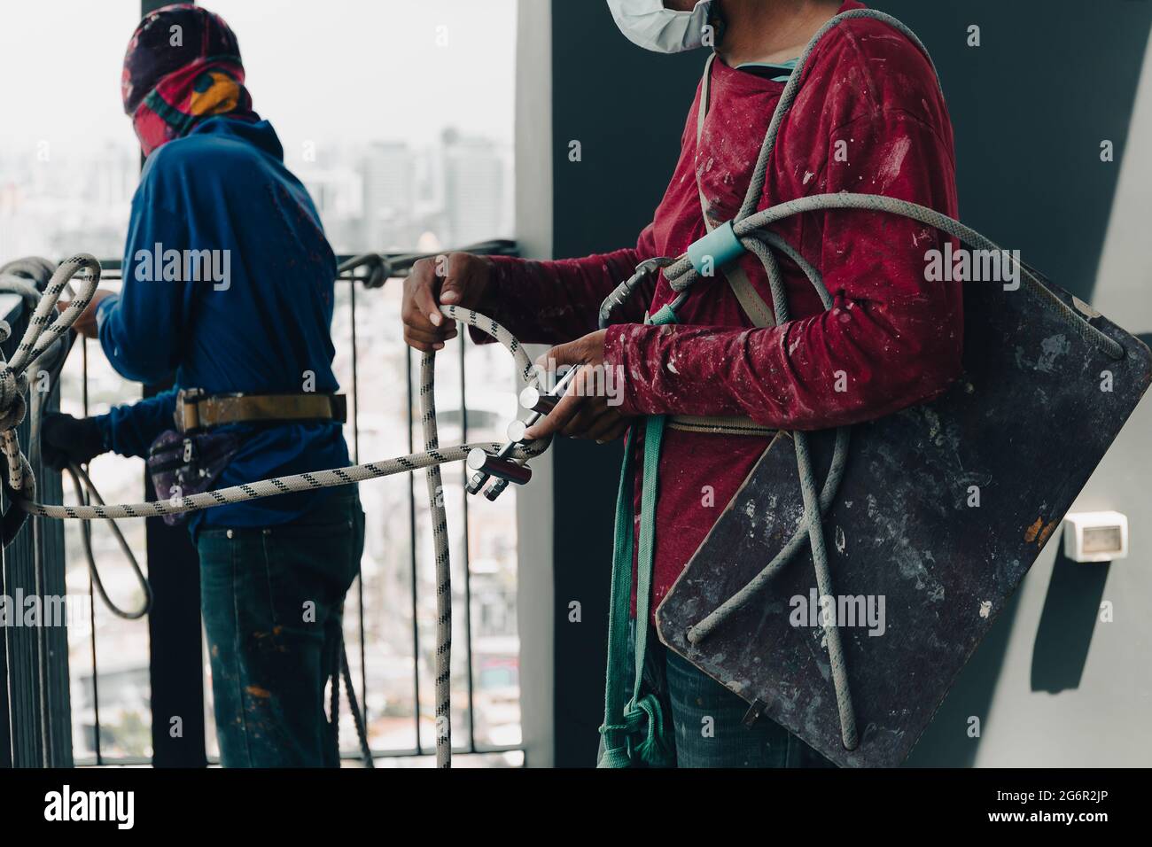 Operatore industriale che regola l'attrezzatura da arrampicata che prepara la fune di sicurezza. Foto Stock