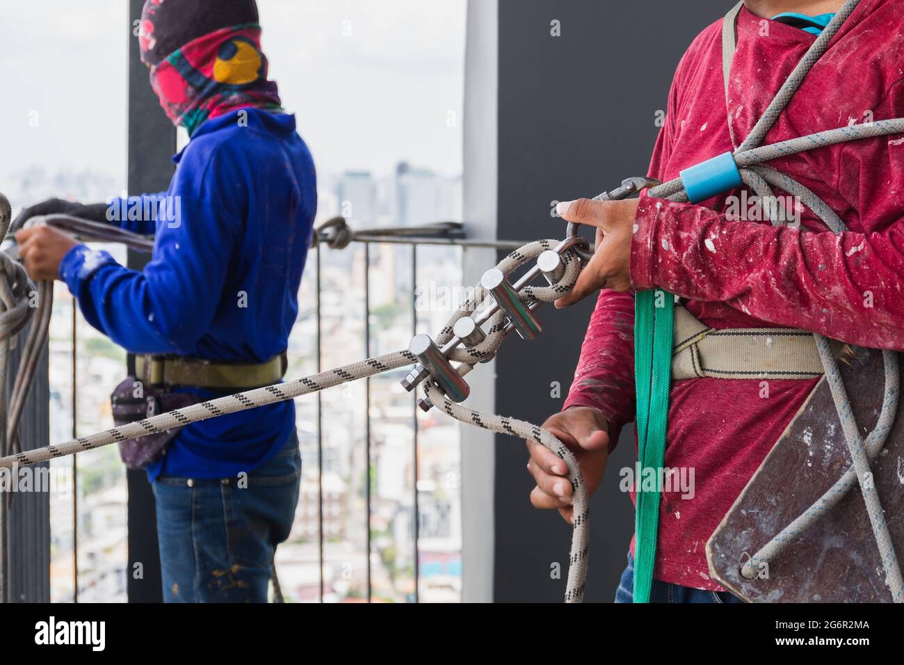 Operatore industriale che regola l'attrezzatura da arrampicata che prepara la fune di sicurezza. Foto Stock