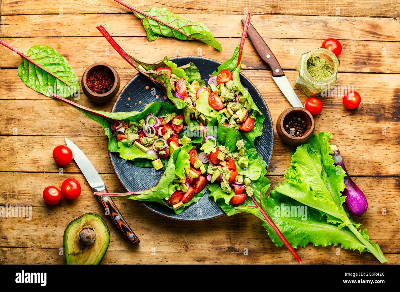 Insalata di avocado, pomodoro con salsa all'aglio in foglie di bietole. Insalata di vitamina estiva in piatto Foto Stock