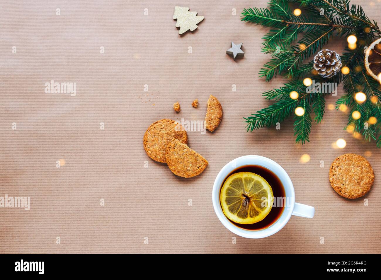 Natale e Capodanno di sfondo. Rami dell'albero di Natale, tazza di tè e biscotti su sfondo beige. Vista dall'alto, disposizione piatta, spazio per la copia Foto Stock