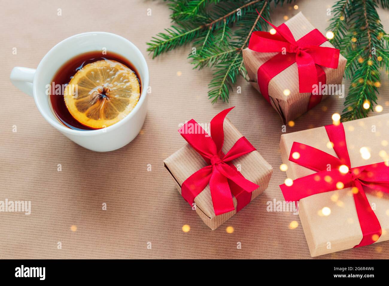 Natale e Capodanno di sfondo. Rami dell'albero di Natale, scatole regalo, tazza di tè e biscotti su sfondo beige. Vista dall'alto, disposizione piatta, copia Foto Stock