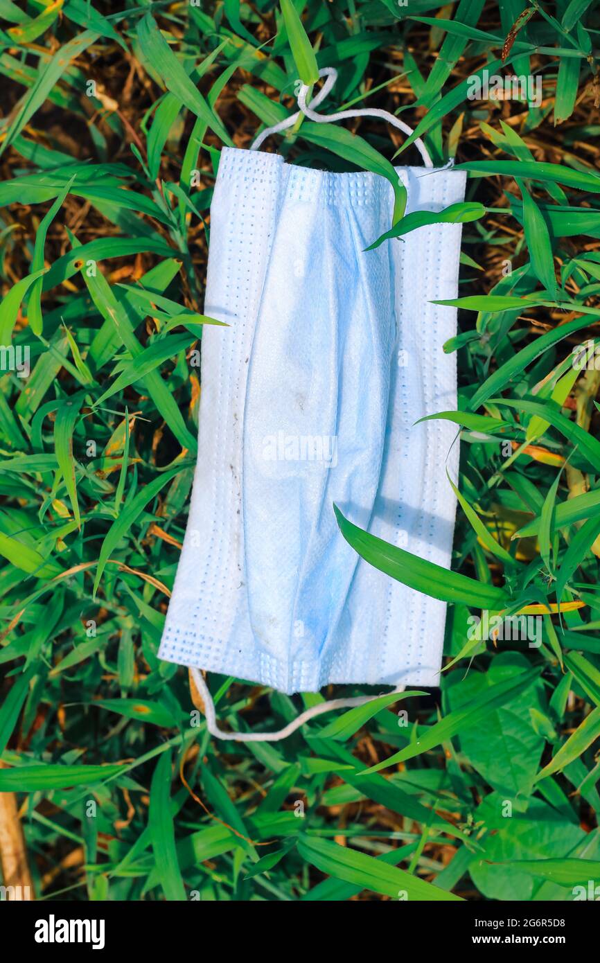 Maschera chirurgica usata, maschera chirurgica gettata sull'erba, inquinamento ambientale e le conseguenze di un uso eccessivo di maschere chirurgiche durante il coronavirus. Foto Stock
