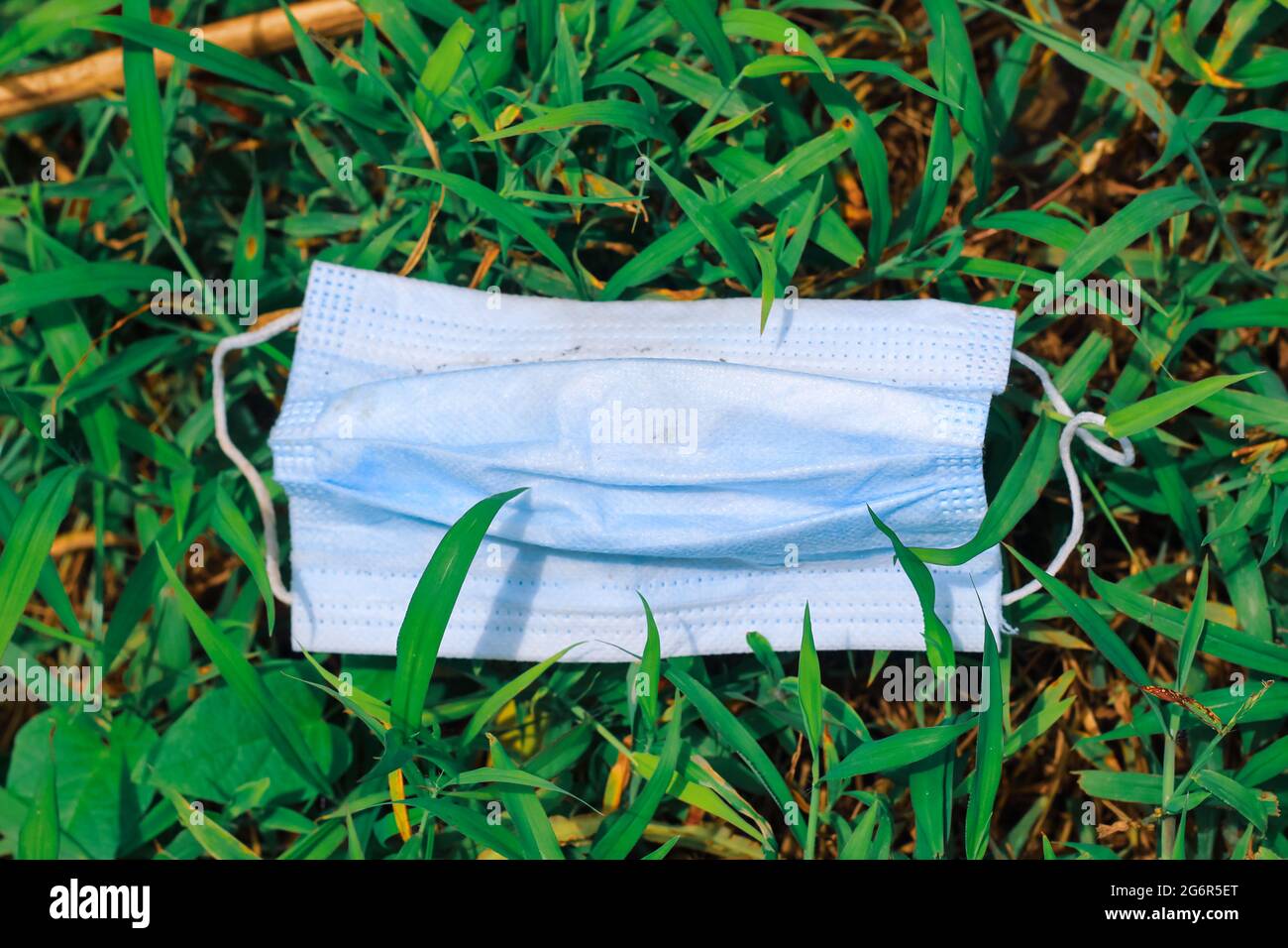 Maschera chirurgica usata, maschera chirurgica gettata sull'erba, inquinamento ambientale e le conseguenze di un uso eccessivo di maschere chirurgiche durante il coronavirus. Foto Stock