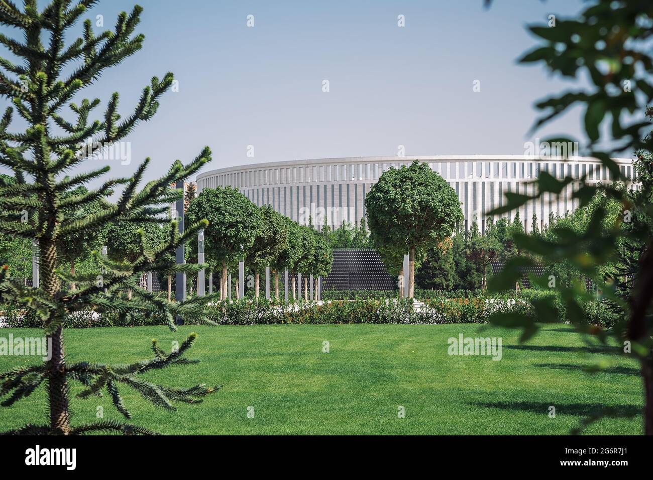 Parco cittadino di Krasnodar o Galitsky Park. Paesaggio con erba verde, alberi decorativi e la facciata bianca dello stadio Foto Stock