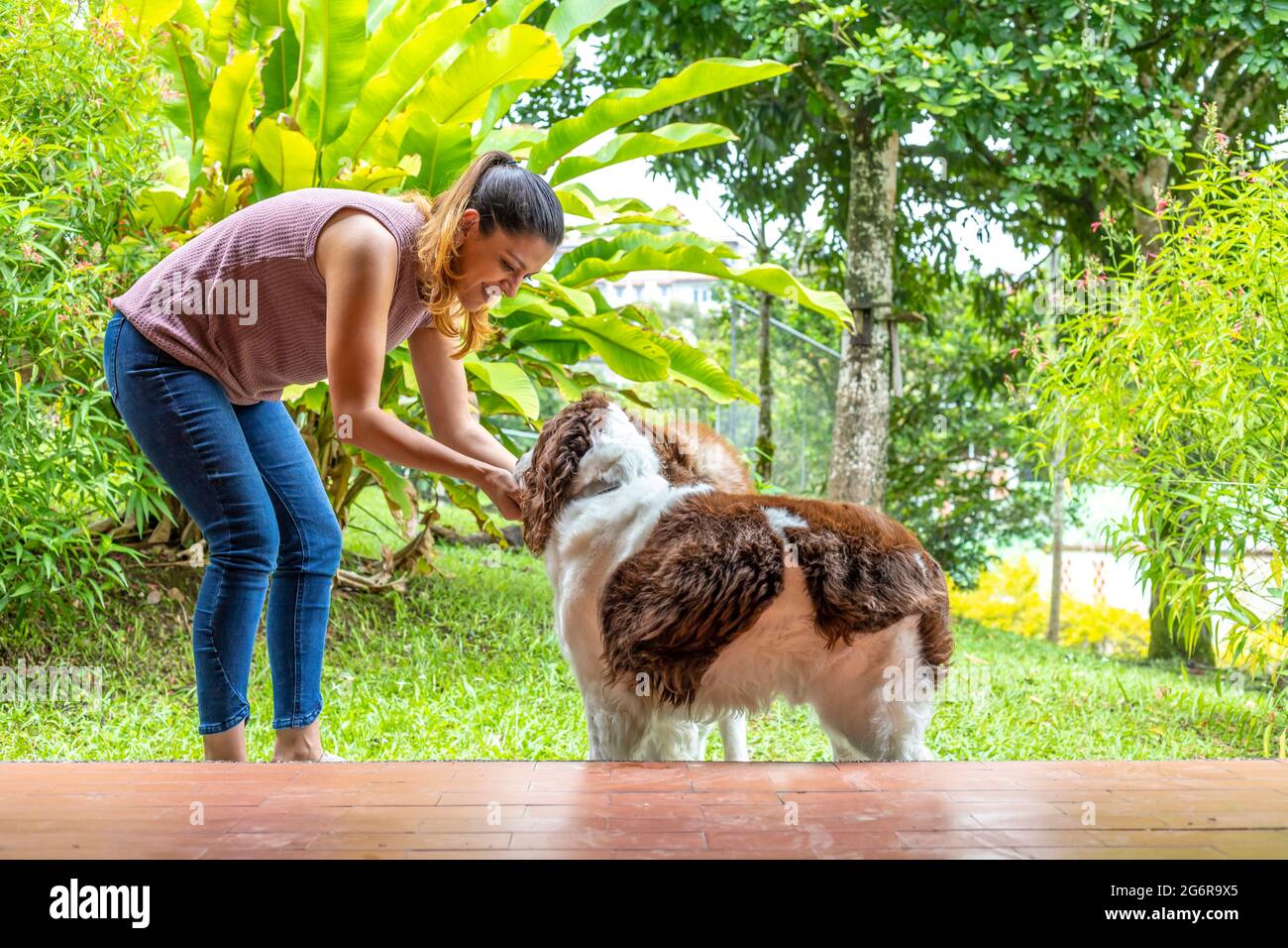 giovane donna che accarezzava i suoi due cani nel giardino della sua casa Foto Stock