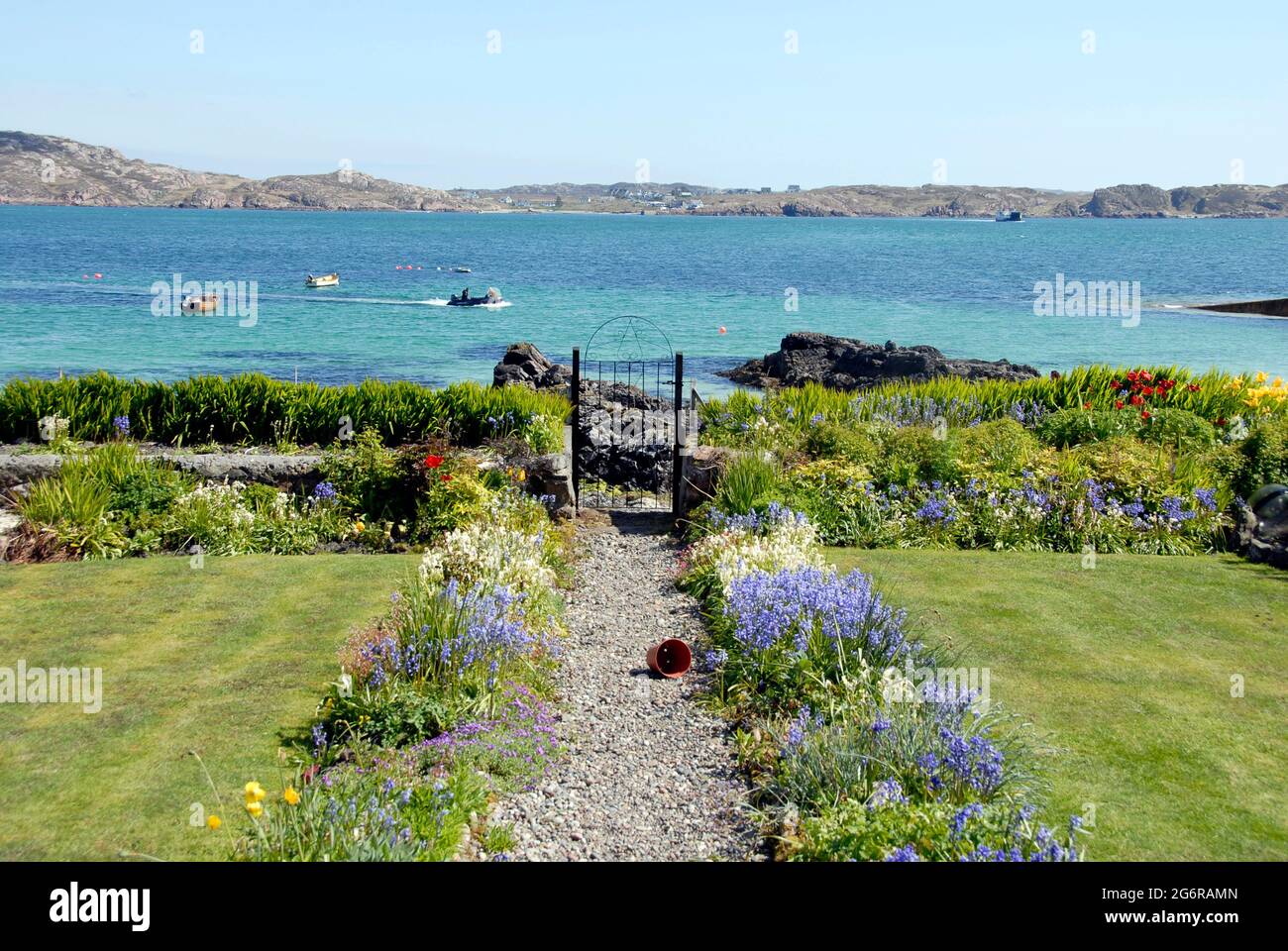 Giardino di casa che si affaccia sul breve tratto d'acqua che separa Iona da Mull, Iona, Scozia Foto Stock