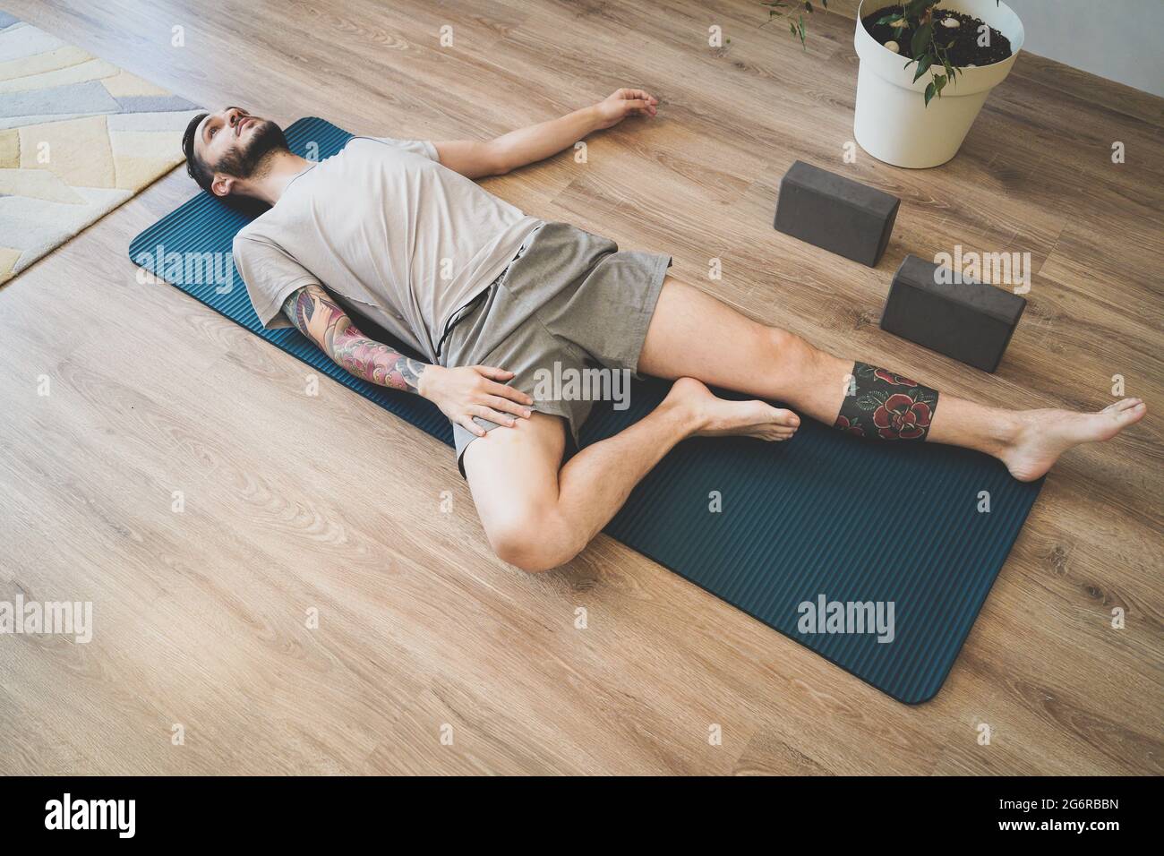 Giovane uomo sdraiato sul tappeto yoga rilassante e respirazione profonda.  Meditando sul tappetino sportivo Foto stock - Alamy