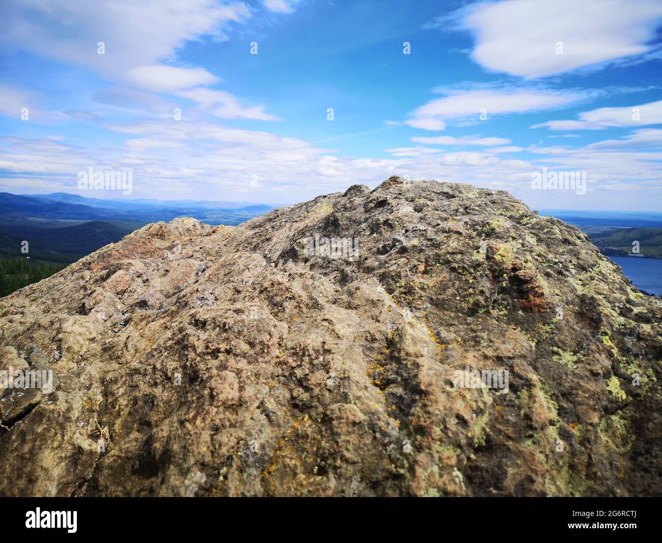 Una grande pietra sullo sfondo di montagne con alberi Foto Stock