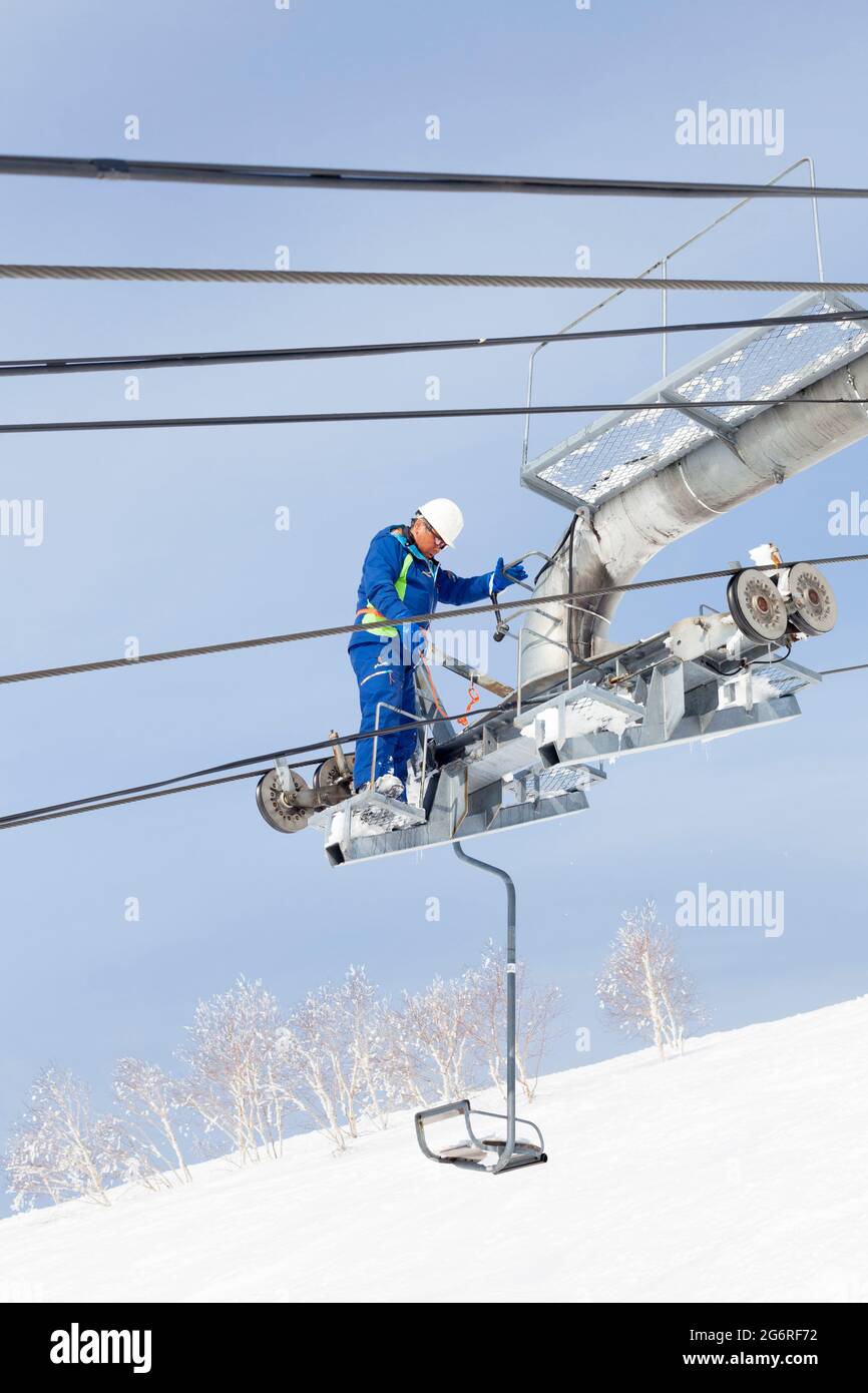 NISEKO, GIAPPONE - 9 marzo : UN tecnico di manutenzione ispeziona una seggiovia a Niseko, Giappone, il 9 marzo 2012. Le piste da sci e gli alberi innevati di Nis Foto Stock