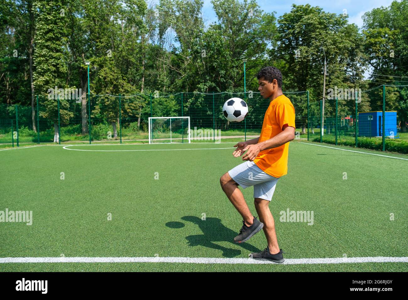 Giovane giocatore di calcio brasiliano calciare e riempire palla di calcio all'aperto Foto Stock