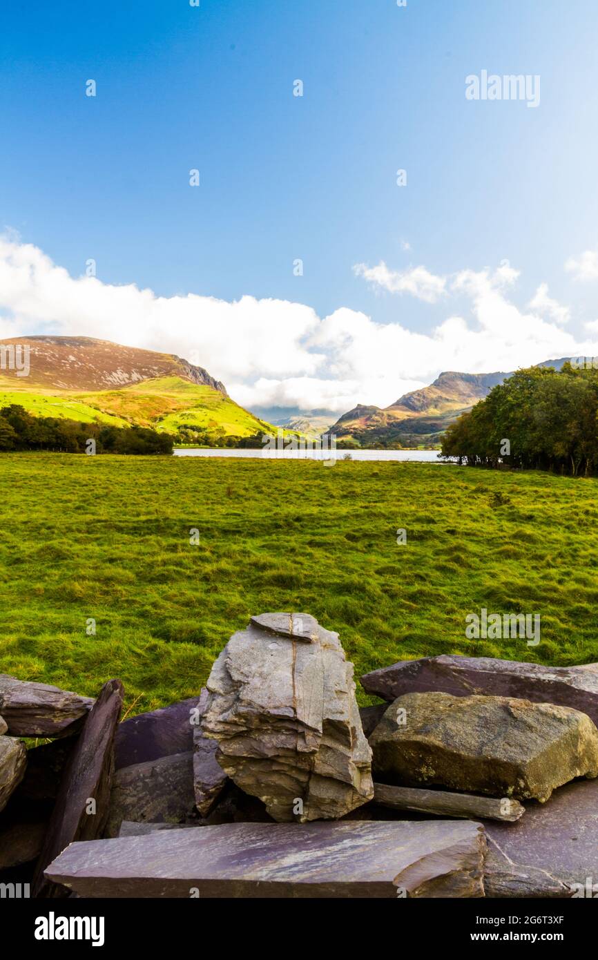 Vista sul lago Nantlle verso Snowdon, Snowdonia, Galles del Nord, Regno Unito, parete in pietra in primo piano, grandangolo, ritratto Foto Stock
