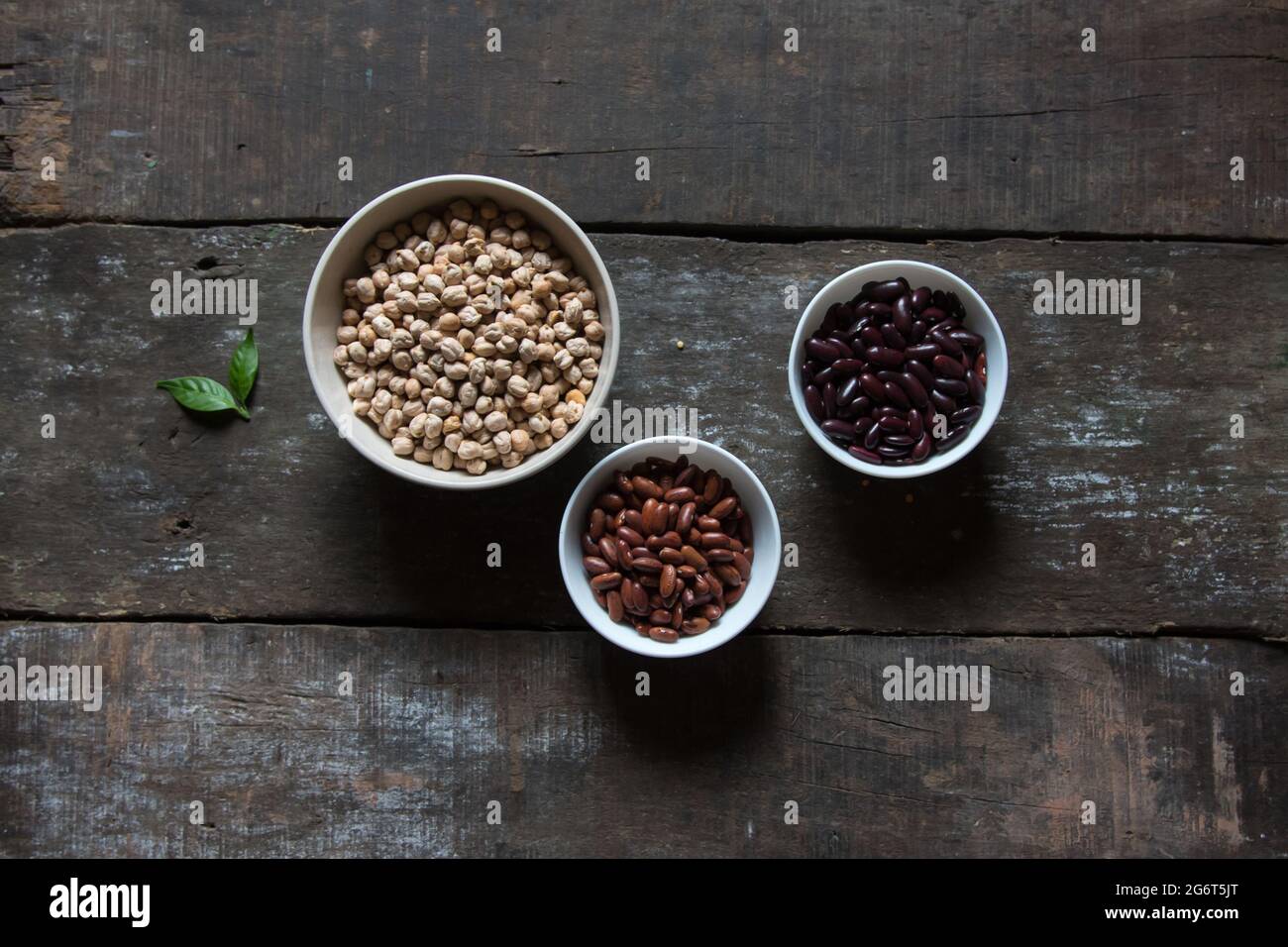 Ingredienti di cibo proteico ceci piselli e fagioli in ciotola su sfondo di legno. Foto Stock Ingredienti di cibo proteico ceci piselli e fagioli in ciotola su sfondo di legno. Foto Stock