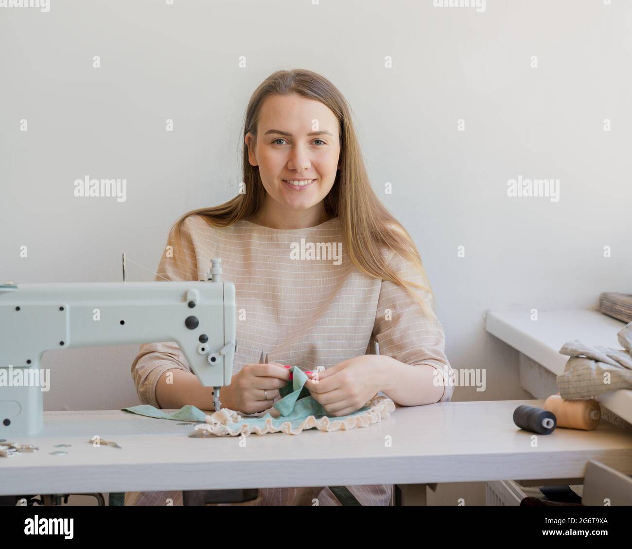 Felice proprietario di atelier che lavora sul suo posto di lavoro con la macchina da cucire Foto Stock