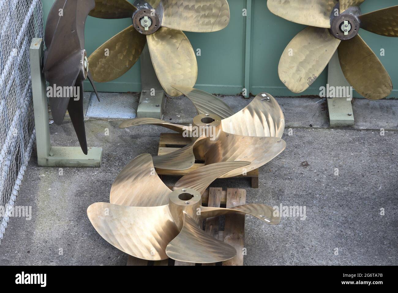 Eliche in ottone di navi o imbarcazioni con cinque pale esposte nel cantiere navale o nel negozio di riparazione vicino al porto, pronte per essere installate su imbarcazioni a motore e crui Foto Stock