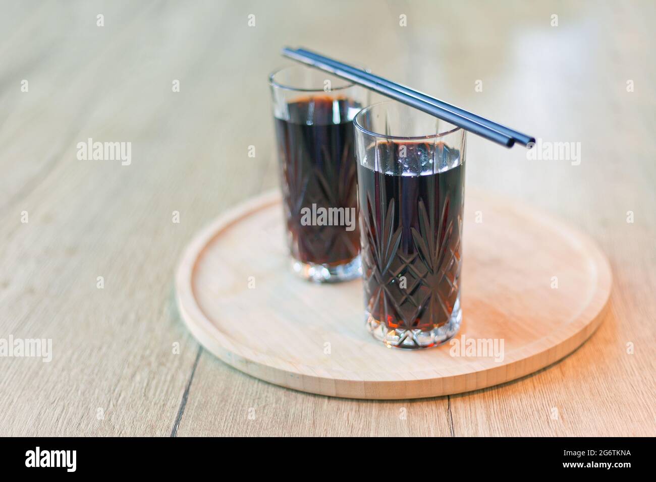 bevanda nera con cannucce. Due bicchieri Cuba Libre o cocktail a base di tè freddo a lunga isola con una cola, ghiaccio, lime, rum con cannucce su tavolo di legno con vista t Foto Stock