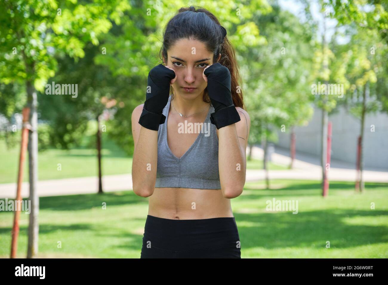 Nessuna persona binaria in mano si avvolge pronta a combattere guardando la telecamera. Muay thai, sport all'aperto. Foto Stock