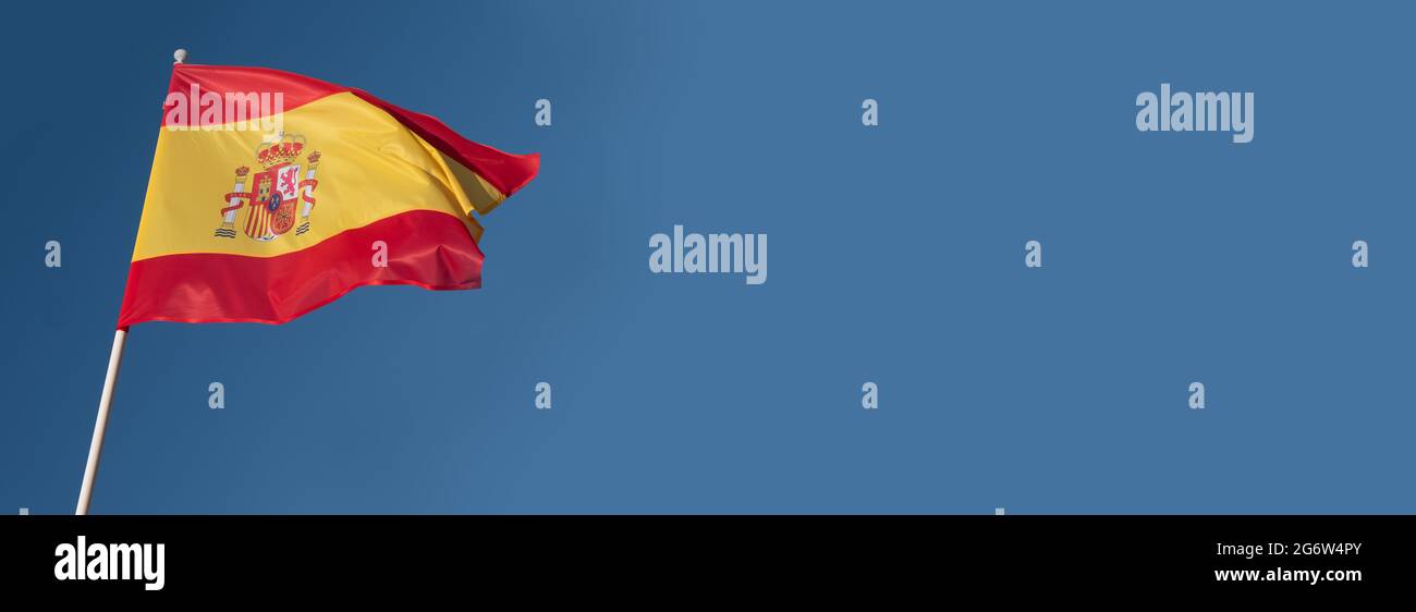 Bandiera della Spagna su sfondo blu cielo. Spazio per la copia vuoto. Bandiera spagnola che oscilla nel vento Foto Stock