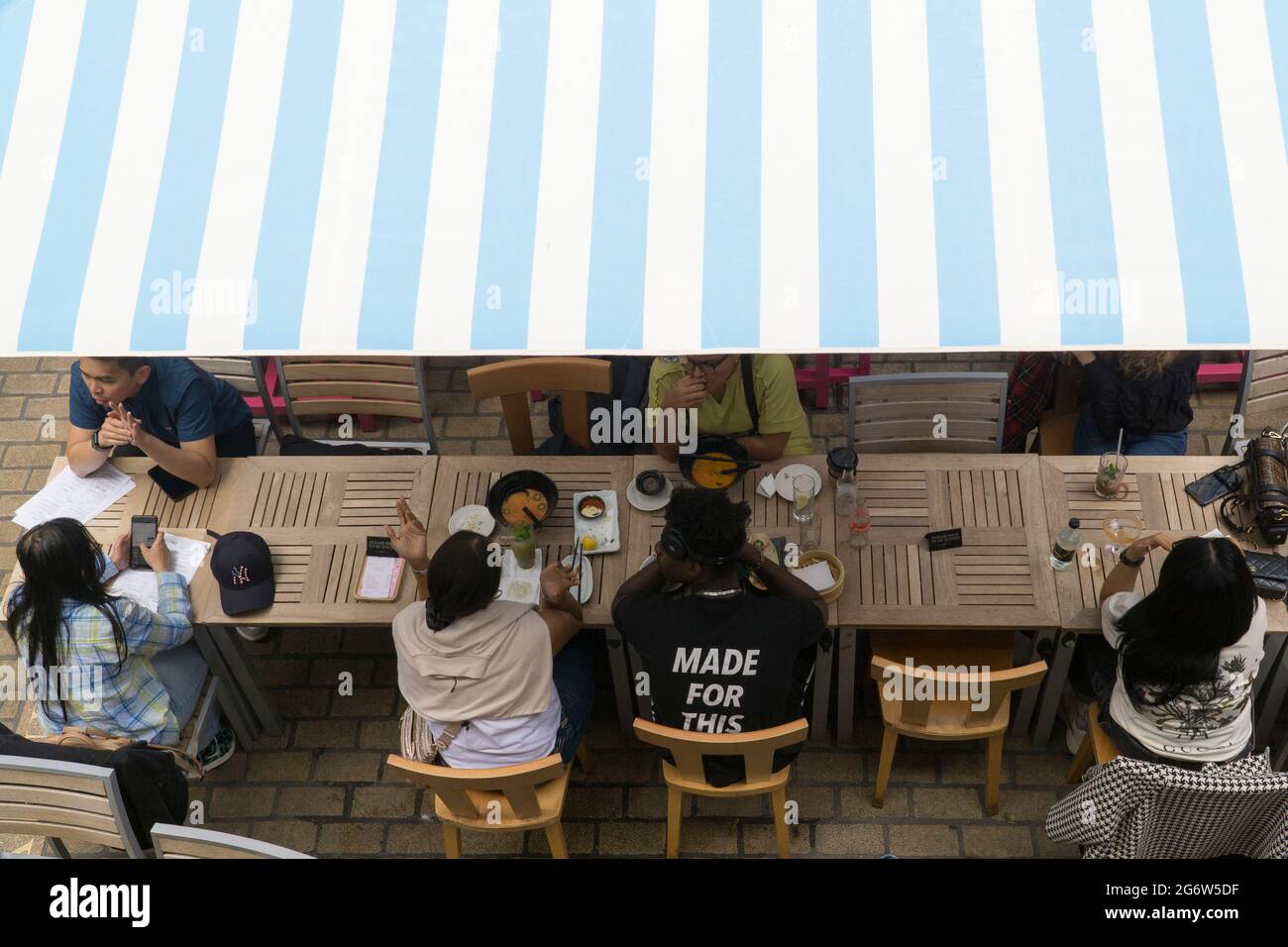 Londra, Regno Unito, 8 luglio 2021: La ristorazione all'aperto rimane l'opzione preferita per molte persone in quanto i casi crescenti della variante Delta causano preoccupazione. A Kingly Court, appena fuori da Carnaby Street di Londra, i commensali e i bevitori possono divertirsi sapendo che uno spazio molto ben ventilato riduce i rischi di trasmissione del coronavirus. I grandi ombrelloni proteggono dalla pioggia e dal sole, che sono entrambi abbastanza probabili in qualsiasi giorno estivo inglese. Anna Watson/Alamy Live News Foto Stock