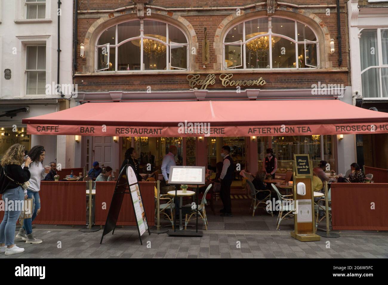 Londra, Regno Unito, 8 luglio 2021: La ristorazione all'aperto rimane l'opzione preferita per molte persone in quanto i casi crescenti della variante Delta causano preoccupazione. OnSouth Moulton Street, appena fuori Oxford Street di Londra, i commensali e i bevitori possono divertirsi sapendo che uno spazio molto ben ventilato riduce i rischi di trasmissione del coronavirus. I grandi ombrelloni proteggono dalla pioggia e dal sole, che sono entrambi abbastanza probabili in qualsiasi giorno estivo inglese. Anna Watson/Alamy Live News Foto Stock