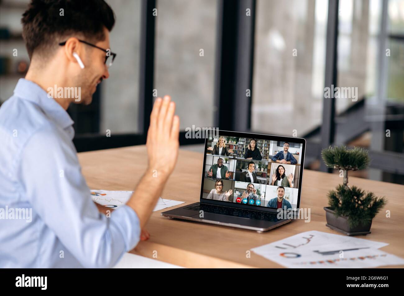 Uomo d'affari di successo caucasico avere una riunione virtuale online con persone diverse, parlare con colleghi multirazziali tramite videochiamata in conferenza utilizzando il laptop, siede in ufficio, saluto interlocutori Foto Stock