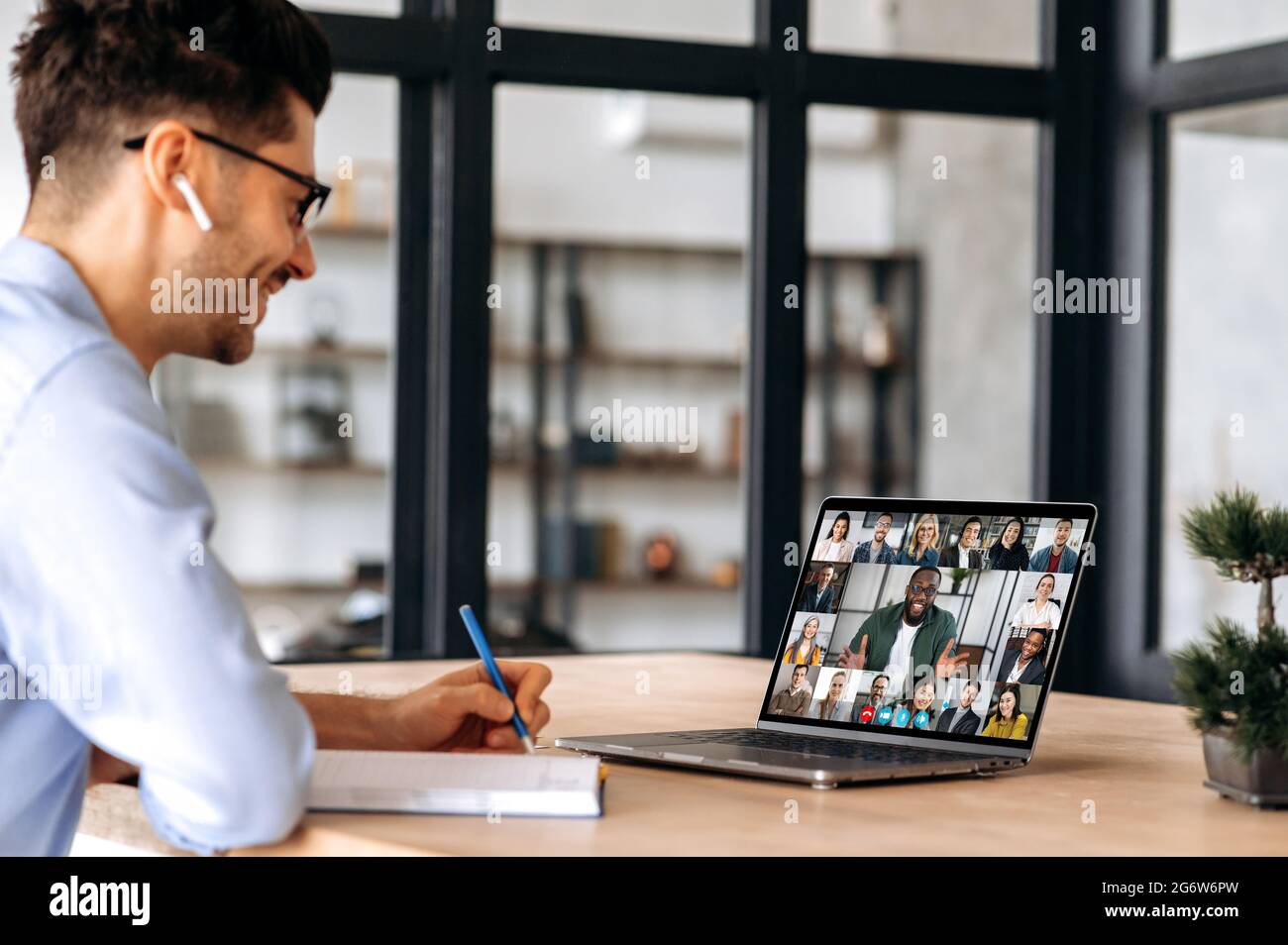 Un manager caucasico di successo, prende appunti durante la riunione di business online con colleghi multinazionali, utilizzando il laptop, seduto in ufficio, pianificazione strategia di marketing, colleghi di ascolto Foto Stock