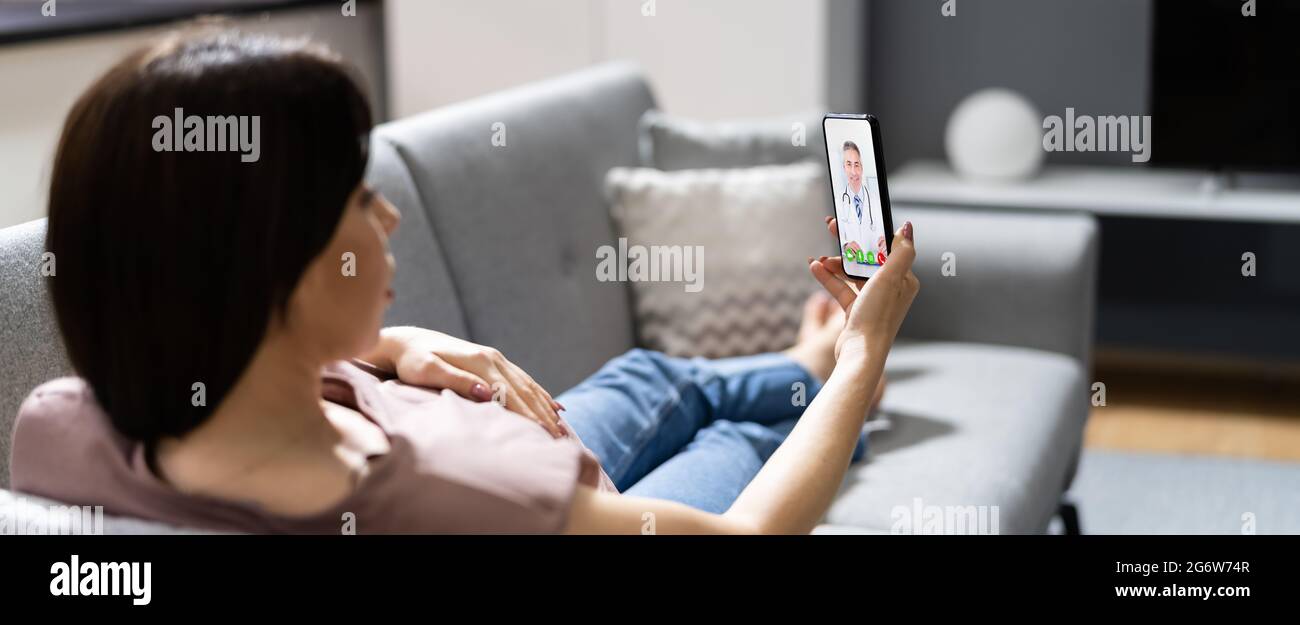 Donna incinta che utilizza la videochiamata online con il medico sul telefono cellulare Foto Stock
