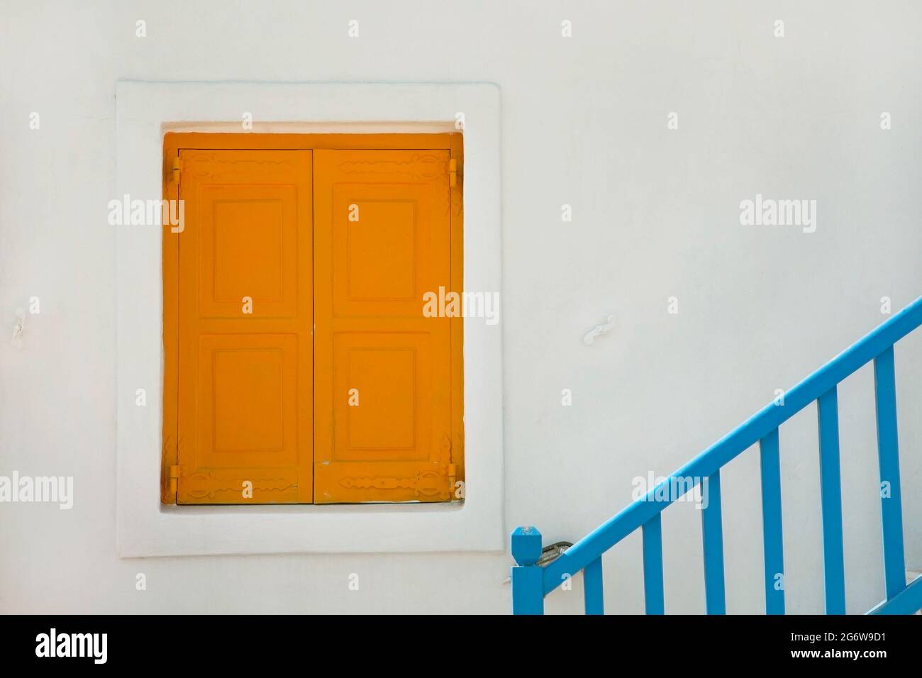 Persiane gialle sulla casa dipinta di bianco con ringhiera blu sull'isola greca di Mykonos Foto Stock
