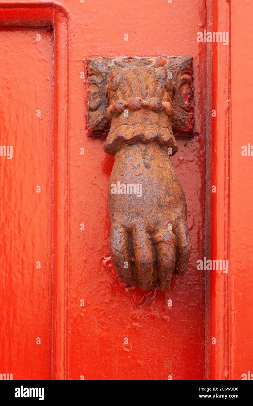 Bussatore in metallo arrugginito a forma di mano su una porta rossa nella città di Mykonos a Chora, nelle isole greche Foto Stock