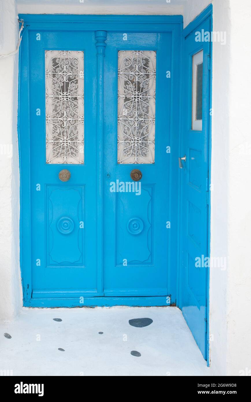 Porte blu con tende bianche in pizzo sulle finestre di Chora sull'isola greca di Mykonos Foto Stock