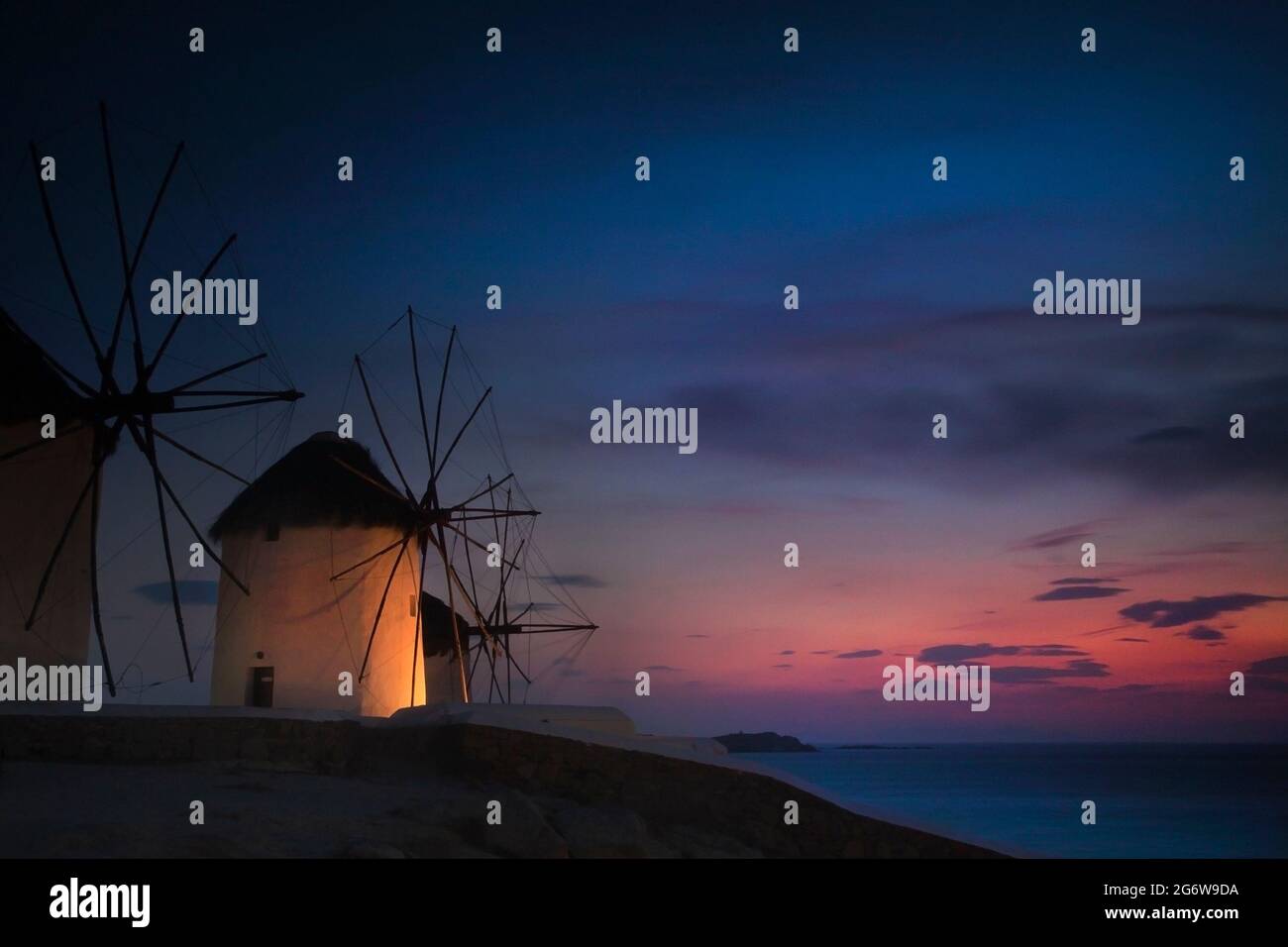 Mulini a vento tradizionali al tramonto, un simbolo distintivo lungo la costa mediterranea dell'isola di Mykonos in Grecia Foto Stock