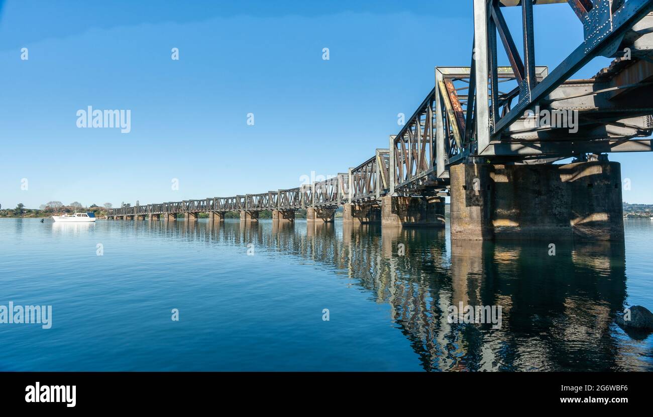 Le linee curvanti dello storico ponte ferroviario a traliccio in acciaio che attraversa il porto di Tauranga dalla città a Matapihi. Foto Stock