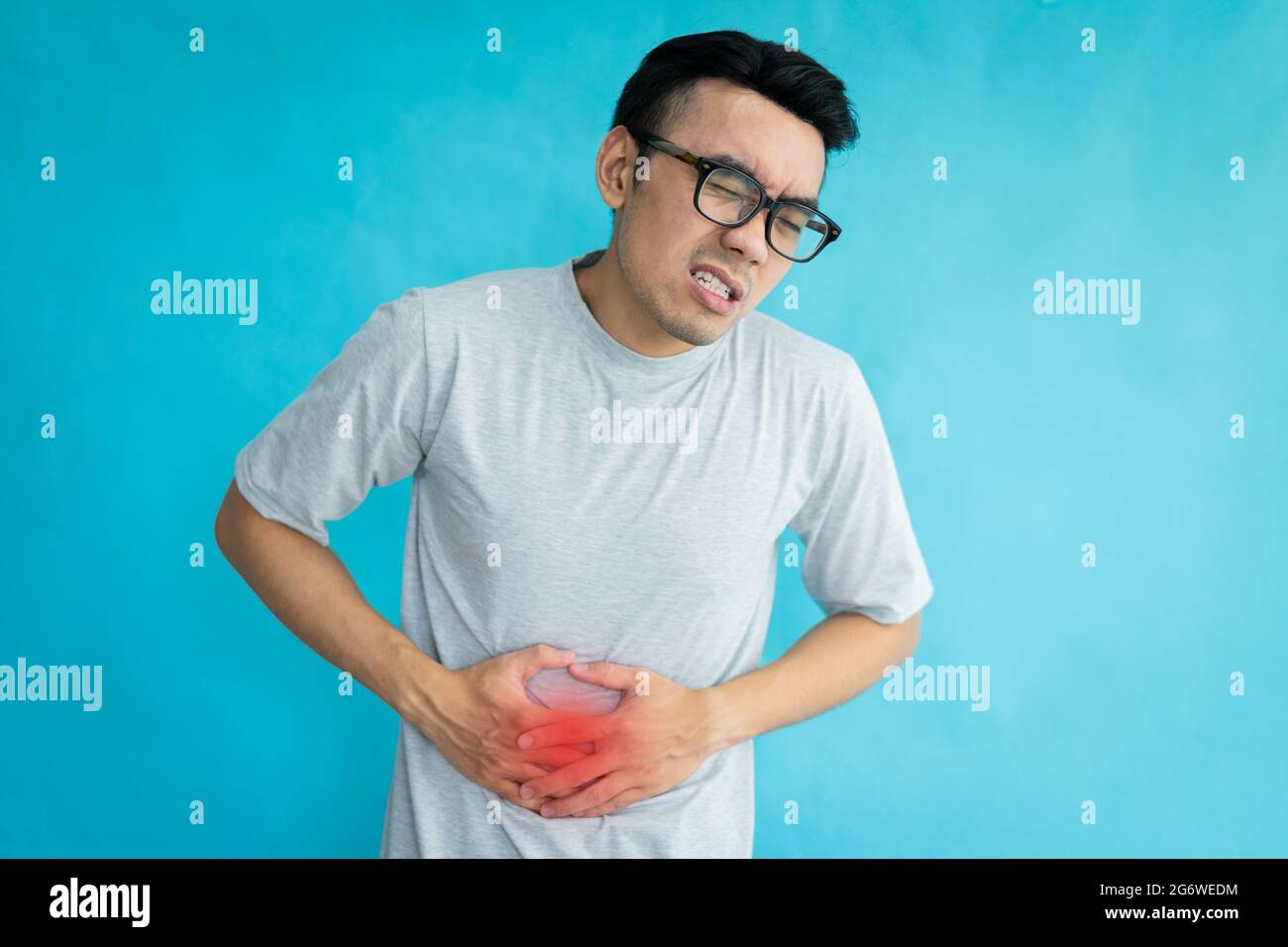 ritratto dell'uomo con stomachache isolato su sfondo blu Foto Stock