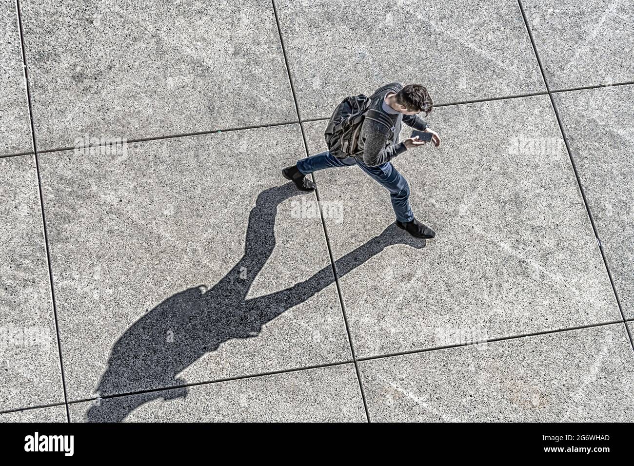 Uomo che invia SMS su un telefono cellulare in ambiente urbano mentre si cammina Foto Stock