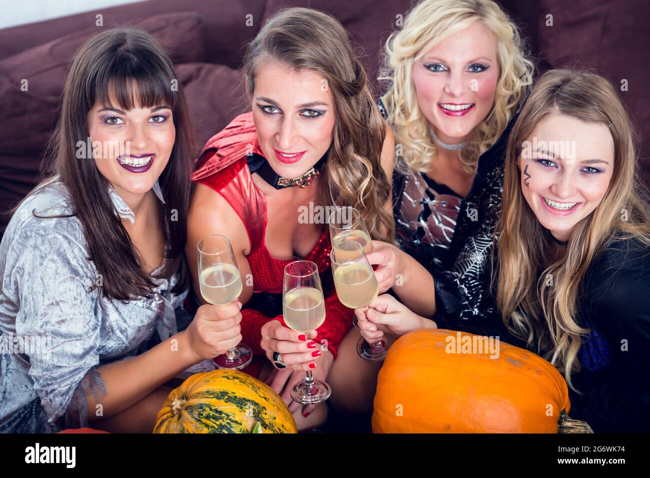 Giovane e bella donna che posa divertente e spaventoso mentre tostando con i suoi migliori amici durante la festa in costume di Halloween Foto Stock