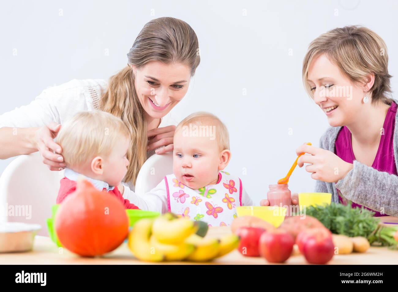 Ritratto di una donna allegra e la giovane madre di un simpatico baby girl, imparando da il suo migliore amico come preparare un sano cibo solido da ingred naturale Foto Stock