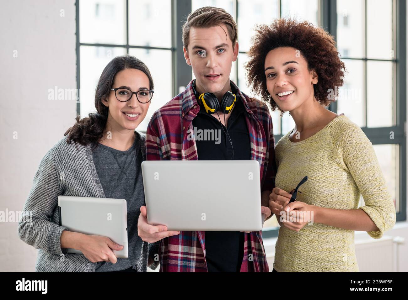 Giovani allegro team di tre persone a guardare un video o cerca su una presentazione aziendale su laptop in ufficio Foto Stock