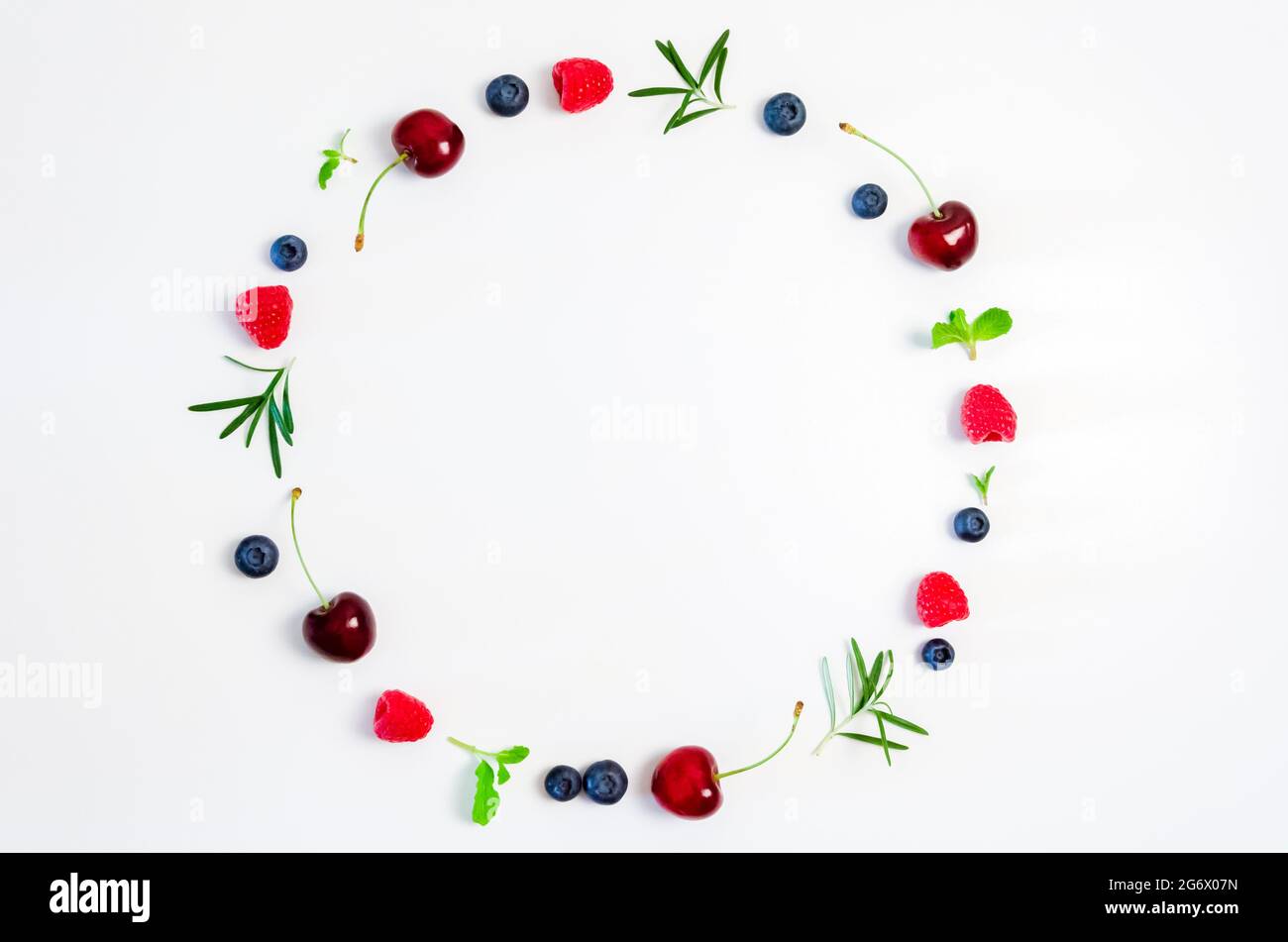 Ciliegia fresca, mirtillo, lampone, menta e foglia di rosmarino sulla vista dall'alto con sfondo bianco per un concetto di cibo sano. Foto Stock
