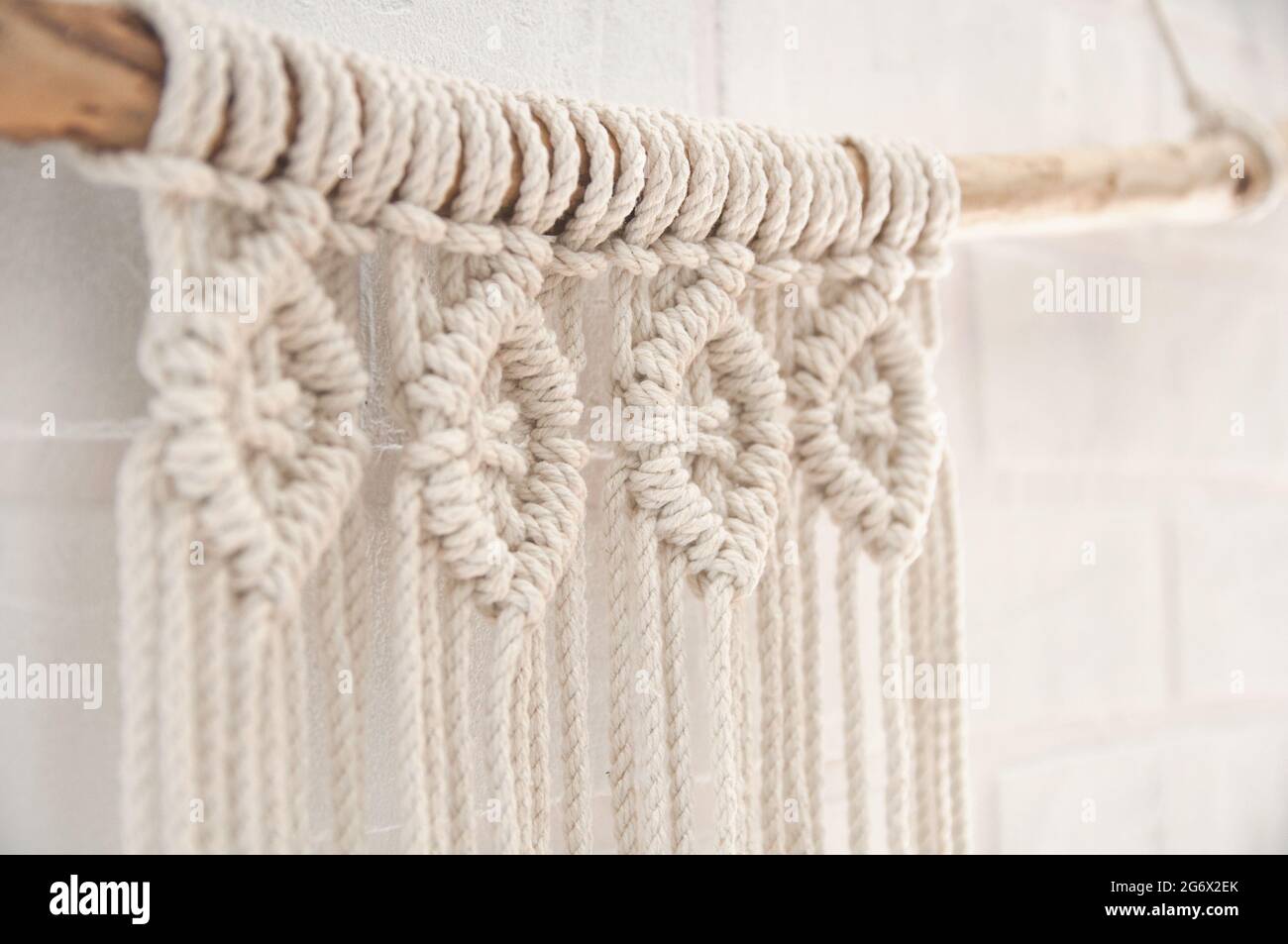 Murale boho murale fatto di fili di cotone di colore naturale usando la tecnica del macrame per l'arredamento domestico e di nozze Foto Stock