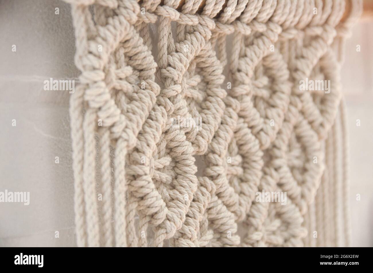 Murale boho murale fatto di fili di cotone di colore naturale usando la tecnica del macrame per l'arredamento domestico e di nozze Foto Stock