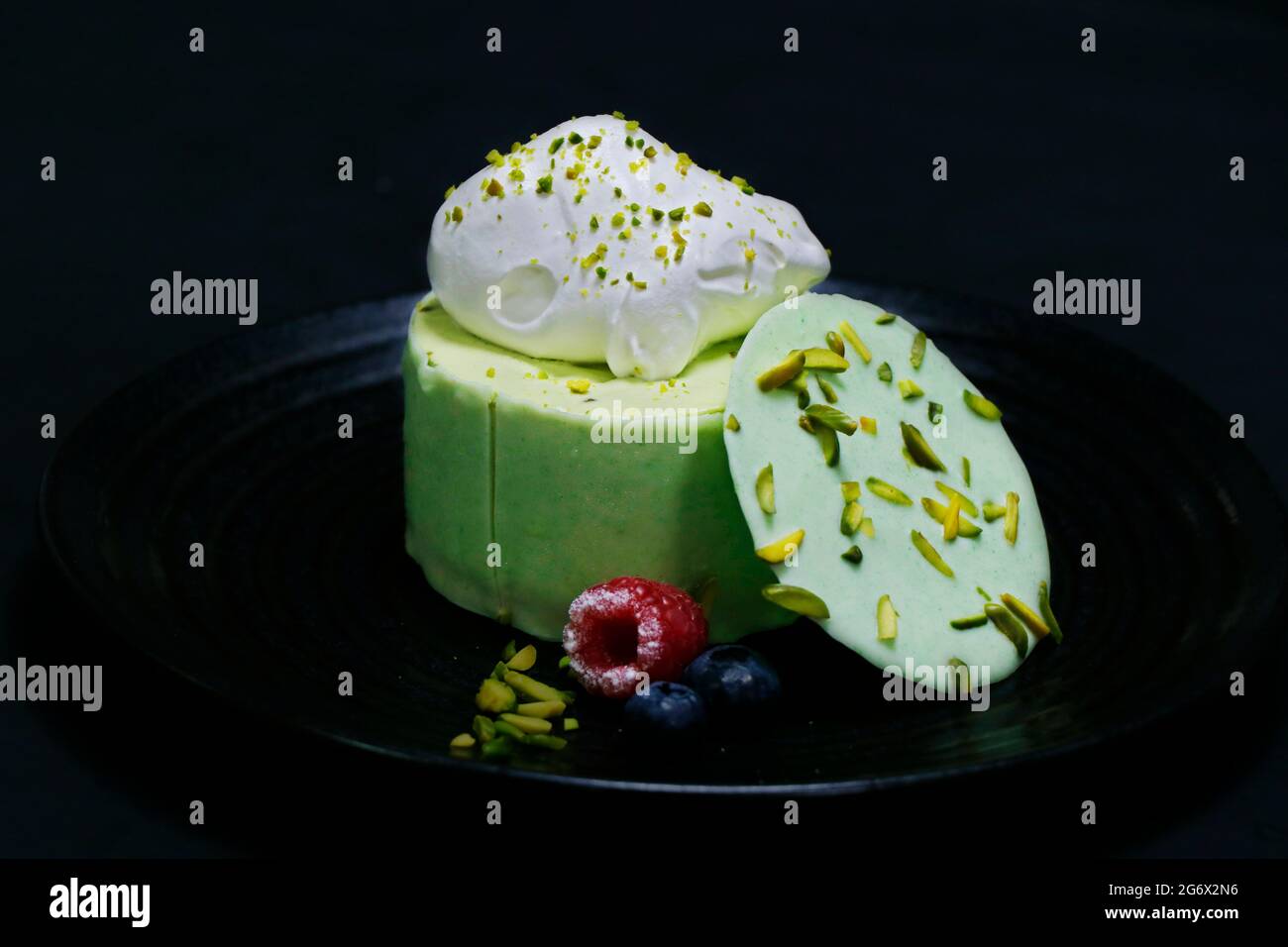 torta di mousse al pistacchio, decorata con frutti di bosco e crema fresca Foto Stock