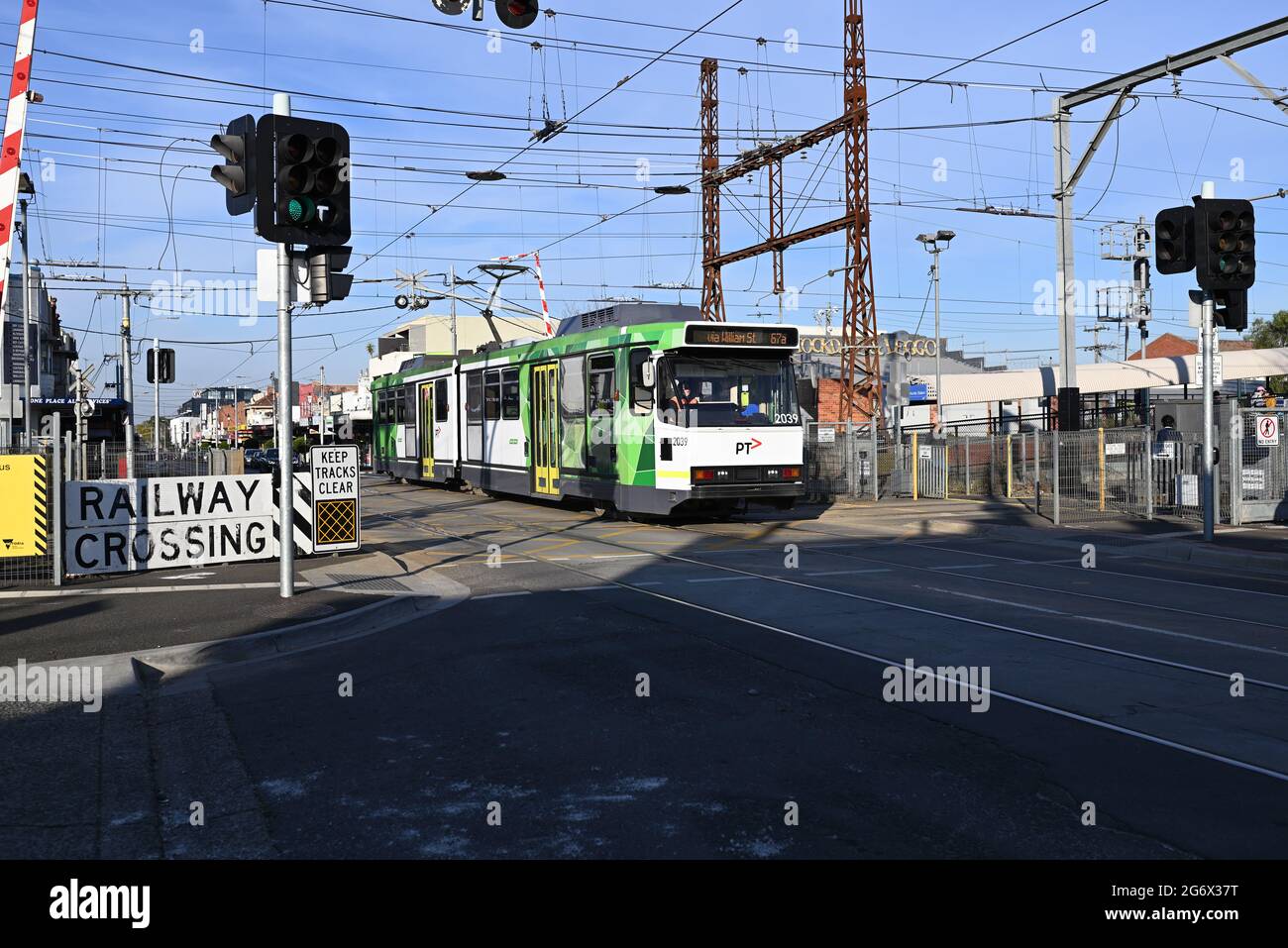 Tram di classe B in direzione della città sulla rotta 67a, gestito dai tram di Yarra, attraversa il livello di Glen Huntly Rd attraversando accanto alla stazione di Glenhuntly in un pomeriggio di sole Foto Stock