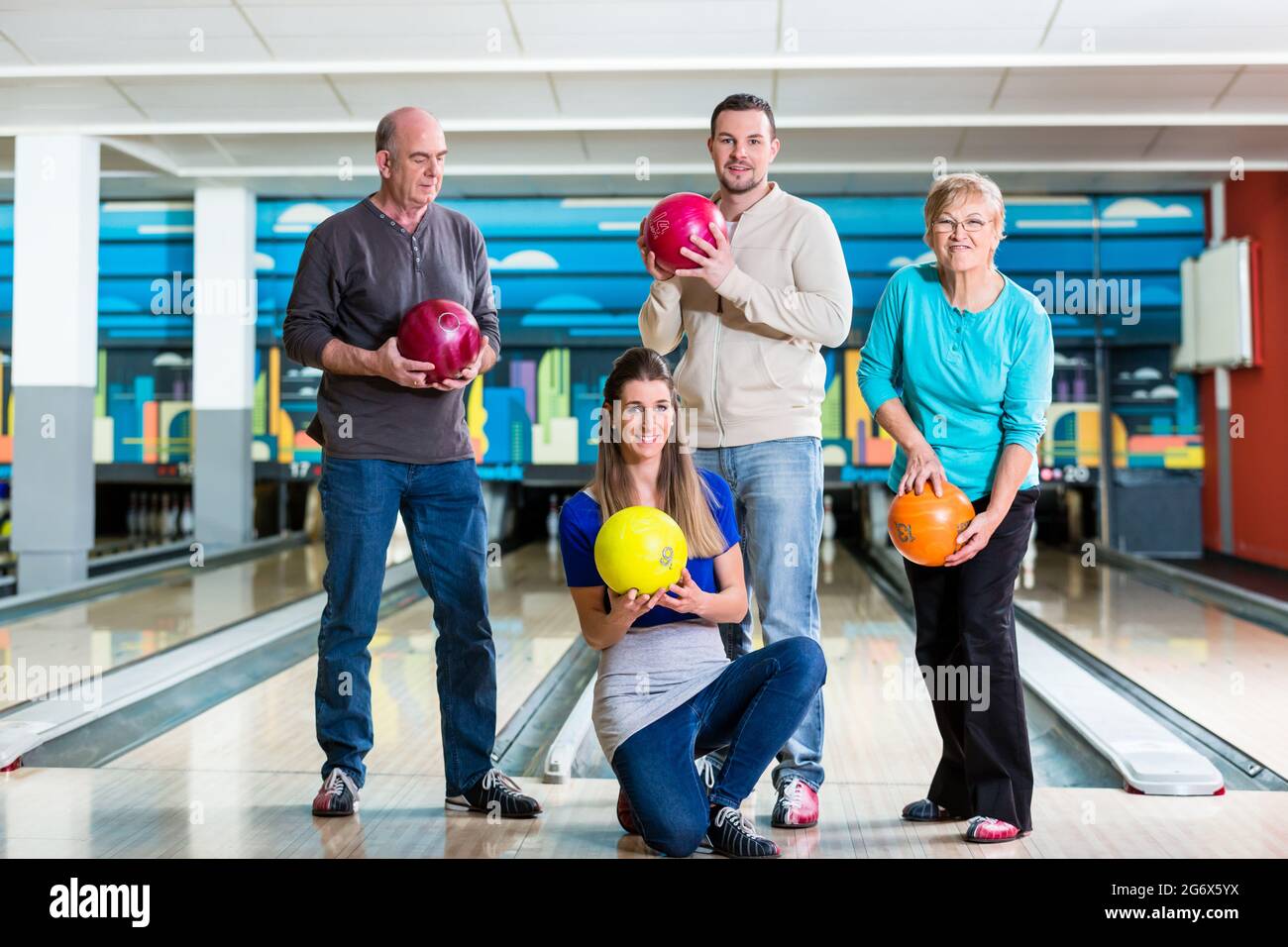 Una famiglia sorridente che tiene in posa una palla da bowling multicolore Foto Stock