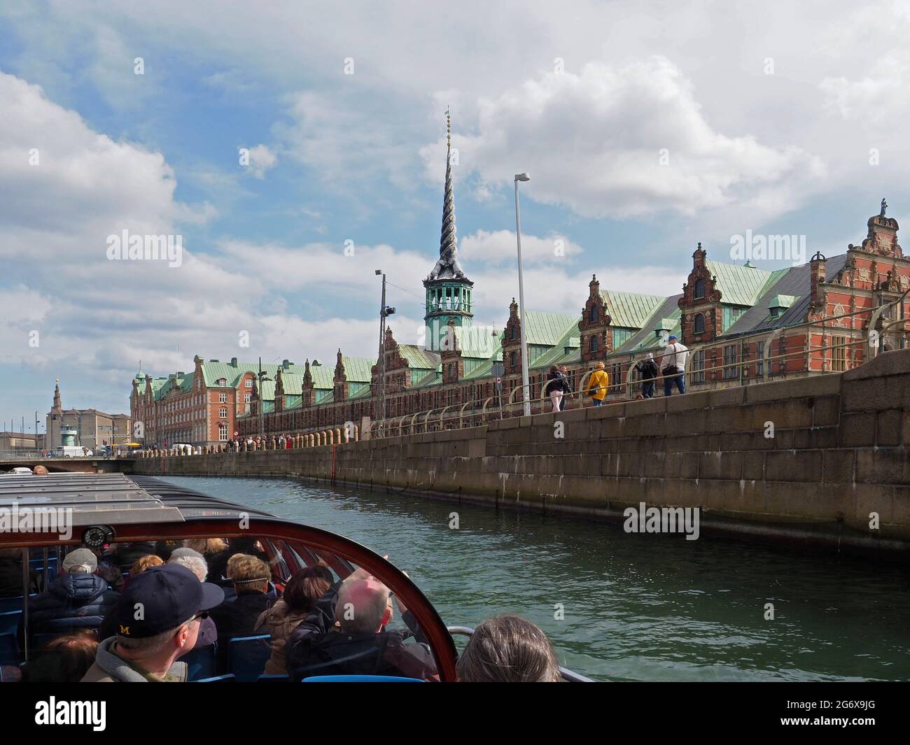 Un tour in barca di Copenhagen che mostra i turisti su una barca che guarda la Borsa, il Palazzo di Christiansborg e la guglia di Dragons Foto Stock