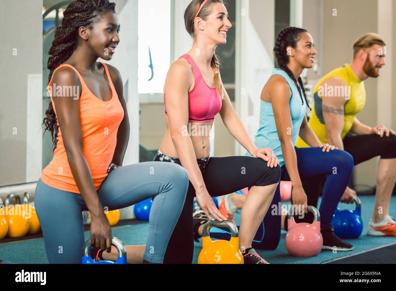 Lunghezza completa di tre giovani e belle determinate persone azienda kettlebells durante l esercizio swing russa durante il training funzionale di classe A Foto Stock