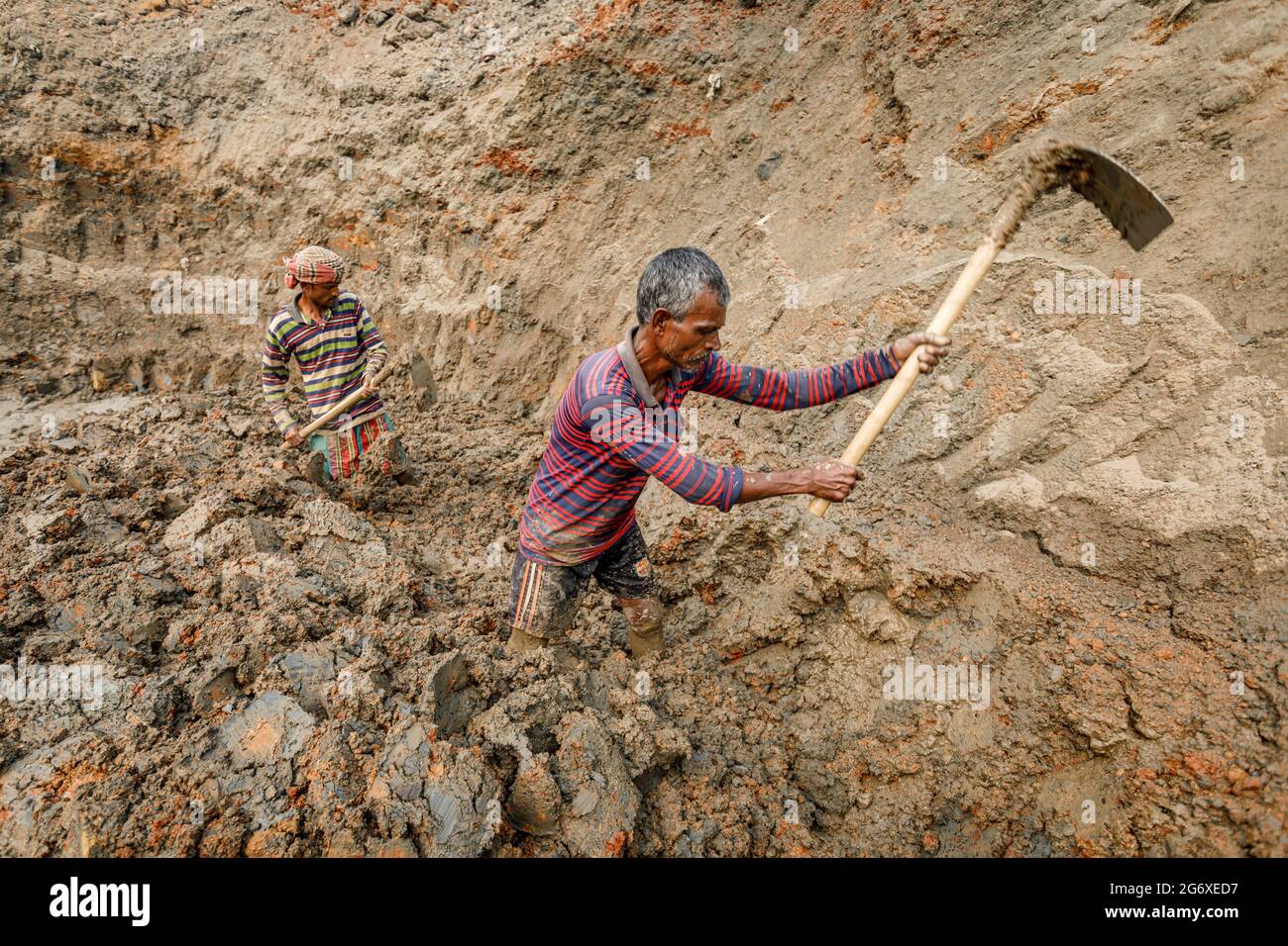 I lavoratori di Brickfield scavano l'argilla dal letto di fiume asciutto in Ashulia per uso come materia prima nella fabbricazione dei mattoni di costruzione. Durante la stagione secca, i letti di fiume esposti si trasformano in brickfields altamente non regolamentati. A causa dell'elevata domanda di materiali da costruzione a basso costo, la produzione di mattoni in argilla è diventata un'industria fiorente in Bangladesh, con forni di produzione fortemente concentrati nelle periferie delle città più grandi. Questi siti di produzione, noti come brickfields, operano utilizzando tecnologie secolari che espellono polvere, cenere, fumo nero e altre sostanze inquinanti negli atmos Foto Stock