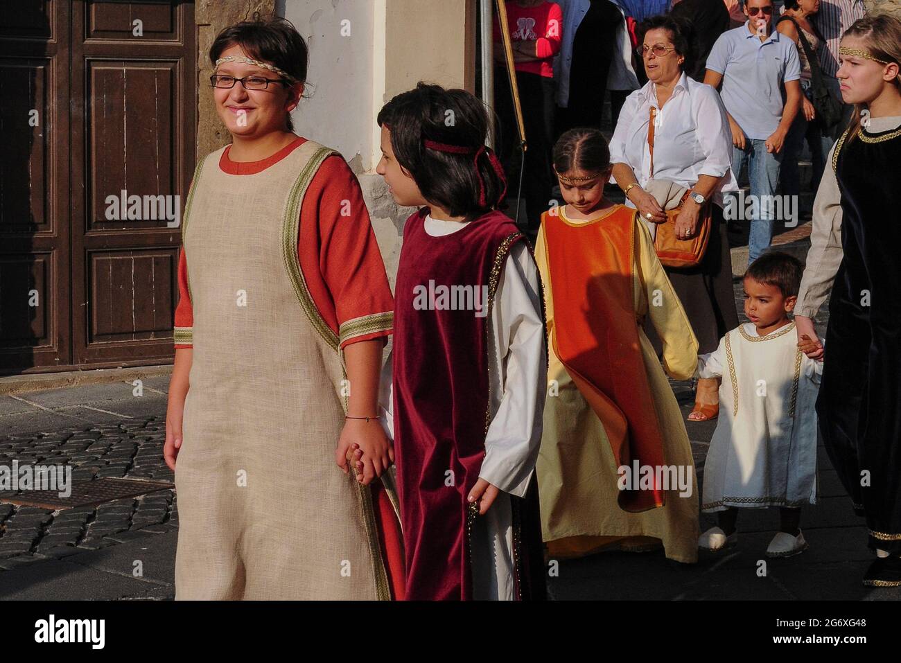 I bambini locali in colorato costume medievale, guidati da un adulto, si  tengono in mano mentre aspettano in Piazza Guglielmo Marconi ad Anagni,  Lazio, Italia, per un segnale di procedere in discesa